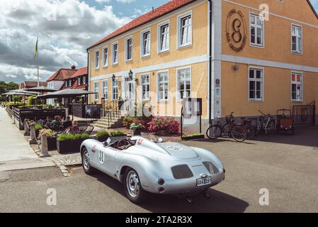 Eine silberfarbene Porsche 718 Spyder Nachbildung parkt vor der Terrasse vor einem Restaurant in aHUS im Sommer, Skåne, Schweden Stockfoto
