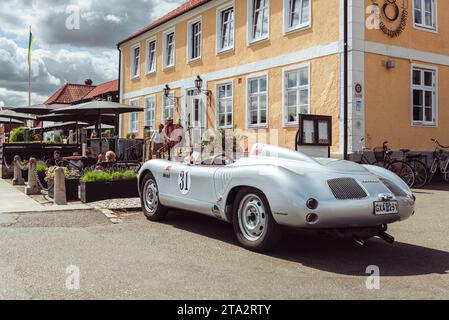 Eine silberfarbene Porsche 718 Spyder Nachbildung parkt vor der Terrasse vor einem Restaurant in aHUS im Sommer, Skåne, Schweden Stockfoto