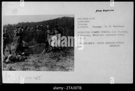 Mitglieder des 1. Platoon, K-Kompanie, der 1. Marine-Division, zeigen feindliche Flaggen, die während der Operation Upshur Stream am am 2. Februar 1971 gefangen wurden. Das Foto zeigt erfasste Ausrüstung, einschließlich Lebensmittel, Flaggen und Vorräte. Dieses Bild wurde von dem Fotografen M. S. Harriman aufgenommen und ist Teil der Sammlung des US Marine Corps, Registrierungsnummer A37373746. Stockfoto