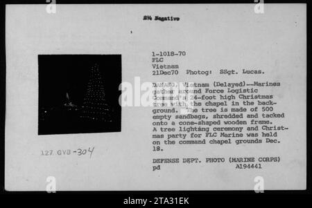 Marines versammeln sich um einen 24 Fuß hohen Weihnachtsbaum aus 500 Sandsäcken in der Nähe einer Kapelle in da Nang, Vietnam; der Baum wurde während einer Weihnachtsfeier für FLC Marines im Dezember 1970 beleuchtet. Stockfoto