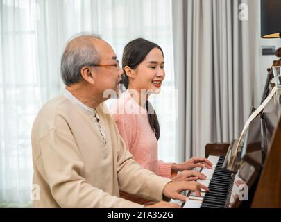 Asiatische junge Frau, die Klavierlehrerin für Seniorenlehrer ist Stockfoto