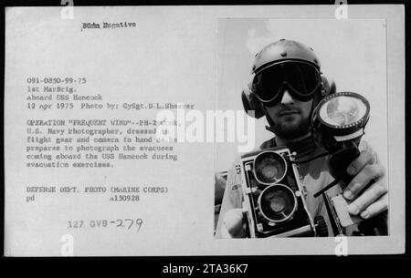 GySgt D.L. Shearer, ein Fotograf der US Navy, bereitet sich darauf vor, Evakuierten, die an Bord der USS Hancock während der Operation Frequent Wind am 12. April 1975 im Rahmen von Evakuierungsübungen zu fotografieren. Stockfoto