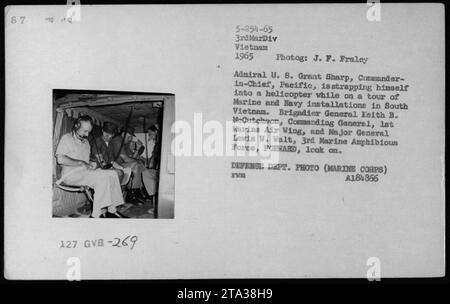 Admiral U. 8. Grant Sharp, CINCPAC, wird während eines Besuchs in Marine- und Navy-Anlagen in Südvietnam gesehen, wie er sich in einen Hubschrauber schnallt. Brigadegeneral Keith B. McCutcheon, Commanding General, 1st Marine Air Wing, und Major General Lewis W. Walt, 3rd Marine Amphibious Force, beobachten. Dieses Foto wurde 1965 von J.F. Fraley als Teil der Dokumentation der amerikanischen Militäraktivitäten während des Vietnamkriegs aufgenommen. Das Bild ist mit DEFENSE DEPT beschriftet. FOTO (MARINEKORPS) A184866 ZWM. Stockfoto