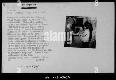 James D. Shelton, Jr., Mitglied der III Harine Amphibious Force, schenkt jungen vietnamesischen Patienten am 16. Dezember 1968 im U.S. Overseas Hission Hospital in da Nang Süßigkeiten. Der Anlass war Teil der Operation Histletos, wo die III. HAF Marines Konzerte und Weihnachtsfeiern für Krankenhäuser, Schulen und Waisenhäuser in da Nang veranstalteten. Stockfoto