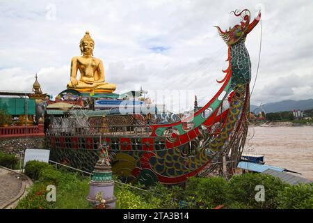 Chiang Saen, Thailand - 4. August 2012: Goldene Buddha-Statue und stilisiertes Stahlboot auf dem Mekong-Fluss im Goldenen Dreieck zwischen Thailand, Laos Stockfoto