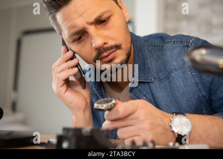 Juweliere, die Armbanduhr reparieren, benutzen das Telefon Stockfoto