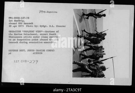 Das Personal des Marine Detachment eskortiert südvietnamesische Piloten zu einem Inspektionspunkt auf der USS Hancock am 29. April 1975, wo Evakuierungsübungen der Operation Frequent Wind durchgeführt werden. Stockfoto