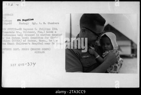 Raymond G. Phillips, Mitglied des US-Militärs, hält ein vietnamesisches Baby in Kleidung, das vom Hudson Youth Committee for Civic Action (HYCCA) an das CoA Khanh Children's Hospital in der Nähe von da Han gespendet wurde. Dieses Foto wurde am 19. April 1968 während des Vietnamkrieges aufgenommen. Stockfoto