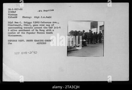 LCpl Don C. Driggs vom US Marine Corps diskutiert das Gelände mit einem südvietnamesischen Popular Forces-Mitglied nahe der CAP 2-1-4, 14 Meilen südwestlich von da Nang, während Militäroperationen in Vietnam am 13. Juni 1968. Stockfoto