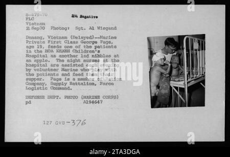 Marine Private First Class George Page, 19 Jahre alt, Freiwillige im HOA KHANH Children's Hospital in Danang, Vietnam. Er wird beobachtet, wie er einen der Patienten füttert, während ein anderes Kind einen Apfel isst. Page, Mitglied der Ration Company, Versorgungsbataillon, Force Logistic Command, hilft den Nachtschwestern, indem sie mit den Patienten spielen und beim Abendessen helfen. Das Foto wurde am 21. September 1970 von Sgt. Al Wiegand aufgenommen und ist Teil der Sammlung, die die militärischen Aktivitäten der USA während des Vietnamkriegs dokumentiert. Stockfoto