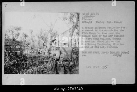 Der Marine-Schützling hält an, um die Schäden zu bewerten, die durch Luftangriffe auf ein vietnamesisches Dorf auf der Van Troung-Halbinsel während der Operation Starlight verursacht wurden, 12 Meilen südlich von Chu Lai, Vietnam. Das Foto wurde am 22. August 1965 von Sgt. Hurley vom US-Verteidigungsministerium aufgenommen. Stockfoto