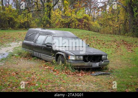 Verlassener Leichenwagen, der im Herbstwald gestrandet ist Stockfoto