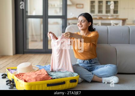 Reisevorbereitung. Junge indianerin, die zu Hause Koffer packt Stockfoto