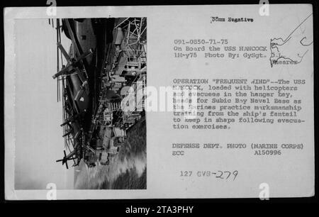 Soldaten an Bord der USS HANCOCK werden während der Operation Frequent Wind im Mai 1975 in Richtung Subic Bay Naval Base gesehen. Das Bild zeigt Evakuierte und Helikopter in der Hangarbucht des Schiffes. Die Marines trainieren weiterhin auf dem Fantail des Schiffes, um nach den Evakuierungsübungen einsatzbereit zu bleiben. Foto des Verteidigungsministeriums von Gysgt. Pole Eares. Stockfoto