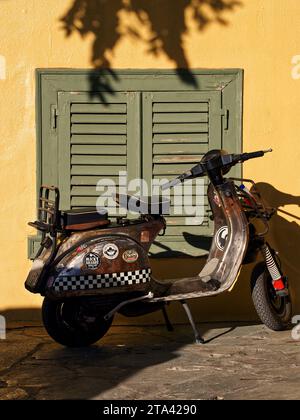 Roller parkte in der Straße vor der gelben traditionellen Gebäudewand Stockfoto