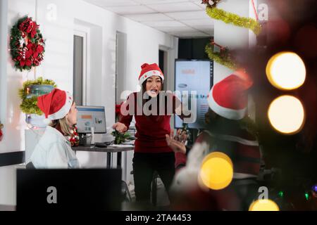 Manager wütend auf Mitarbeiter, frustriert über die schwache Unternehmensleistung, nachdem er während der Weihnachtszeit die Analysen zum Jahresende überprüft hatte. Die Geschäftsleitung schrie die Angestellten in einem festlich dekorierten Büro an Stockfoto