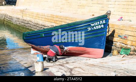 Essaouira, Marokko - 17. September 2022: Mann malte das traditionelle blaue Fischerboot im Hafen von Essaouira Stockfoto