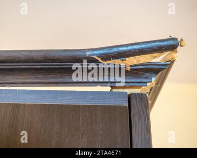 Ecke des Schranks ist gebrochen. Riss in einem Holzschrank. Bruch beim Transport von Möbeln. Muss wiederhergestellt werden. Platinen Stockfoto