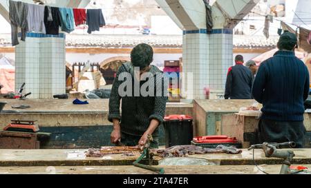 Essaouira, Marokko - 17. September 2022: Marokkanische Fischer reinigen und bereiten einen Tintenfisch zum Verkauf auf dem Essaouira-Fischmarkt vor Stockfoto