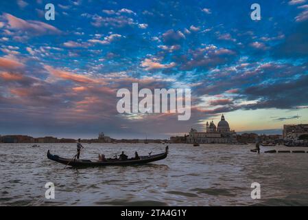 Traditionelle venezianische Gondel schwimmt auf ruhigen Gewässern mit der Skyline der Stadt im Hintergrund Stockfoto