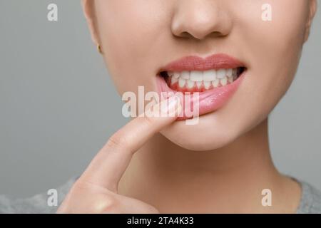 Frau mit entzündetem Kaugummi auf grauem Hintergrund, Nahaufnahme Stockfoto