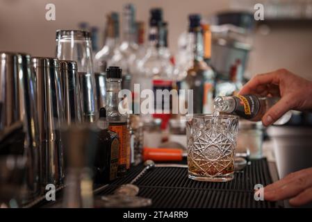 Professioneller Barkeeper, der fachmännisch einen köstlichen Cocktail in ein Glas in einer stilvollen Bar gießt. Stockfoto