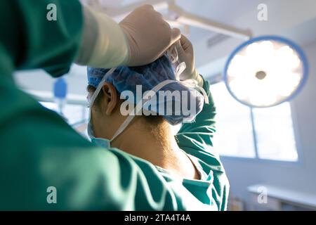 Rücken einer birassischen Chirurgin mit Gesichtsmaske im Krankenhaus-OP Stockfoto