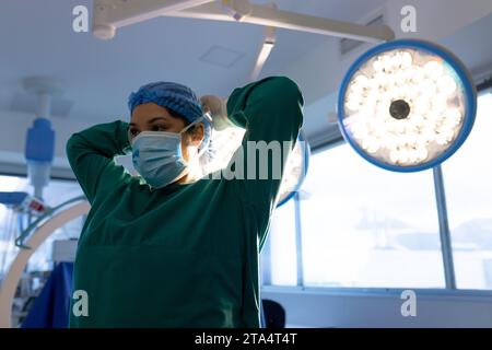 Birassische Chirurgin mit Gesichtsmaske im Krankenhausoperationssaal Stockfoto