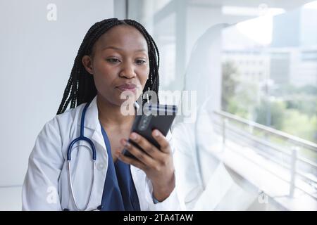 afroamerikanische Ärztin im Labormantel mit Smartphone im Krankenhaus Stockfoto