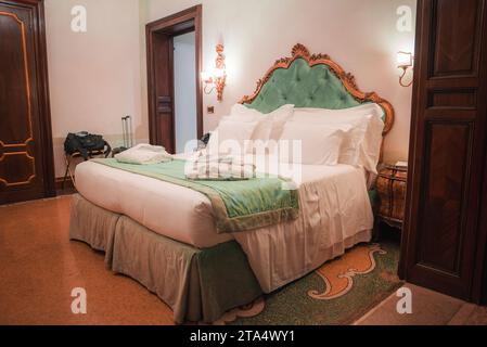 Luxuriöses Kingsize-Bett mit grünem Kopfteil und traditioneller Holzkommode in elegantem Zimmer Stockfoto