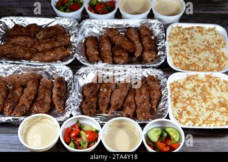 Arabische Küche traditionelles Essen Rindfleisch Kofta, Kufta-Shish, Hackfleisch in Lammfettkohle gewickelt, gegrillt mit grünem und Tahini-Salat und heiß gedünstet Stockfoto