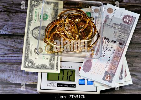 Kairo, Ägypten, 9. November 2023: Stapel Gold auf einer digitalen Ming-Heng-Skala in Gramm mit ägyptischen Pfund und US-Dollar-Bargeld-Banknoten Stockfoto