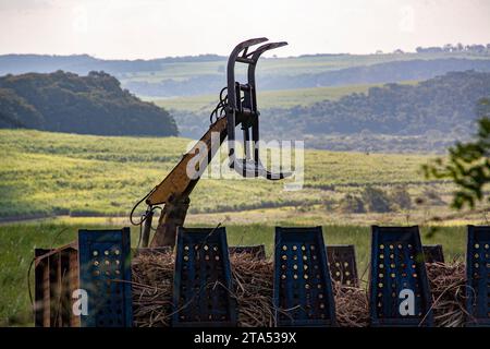 Der Lader für Zuckerrohrgreifer sammelt geschnittenes Zuckerrohr auf dem Boden und lädt den LKW für den Transport zur Mühle für die Ethanol- und Zuckerproduktion. Bauru, Bundesstaat Sao Paulo, Brasilien. Stockfoto