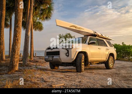 Skyway Beach, FL, USA - 22. November 2023: Toyota 4runner SUV mit Ruderschale, LiteRace 1x von Liteboat auf Dachträgern an einem Strand in Florida. Stockfoto