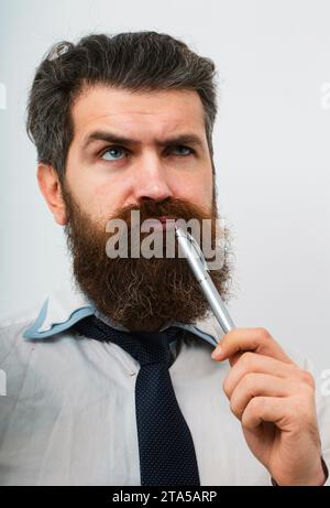 Konzentrierter Mann mit Stift im Mund. Er denkt. Geschäftskonzept. Flucht aus der Krise. Lustiges Gesicht. Tolle Idee. Stockfoto