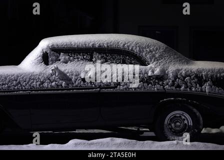 Marktoberdorf, Deutschland. November 2023. Ein schneebedeckter Oldtimer steht am frühen Morgen unter einer Straßenlaterne. Quelle: Karl-Josef Hildenbrand/dpa/Alamy Live News Stockfoto