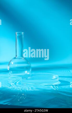 Laborkonzept mit einem Glaspodium, dekoriert mit einem Flachbodenkolben aus florenz. Blauer Hintergrund. Leeres Feld zur Anzeige des Produkts Stockfoto
