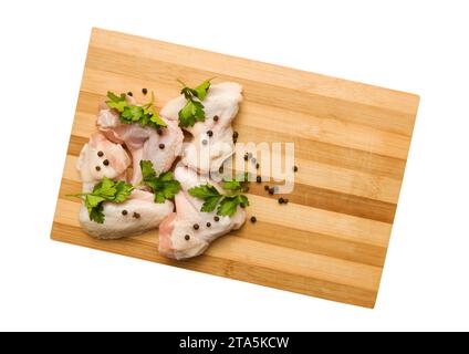 Rohe Hähnchenflügel mit Gewürzen auf einem Schneidebrett mit Schneidepfad. Draufsicht. Stockfoto