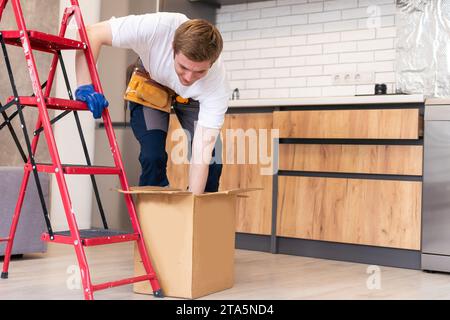 Bewegung, Menschen und Immobilienkonzept - glücklicher lächelnder Mann, der Boxen mit Zeug in einem neuen Zuhause hält Stockfoto