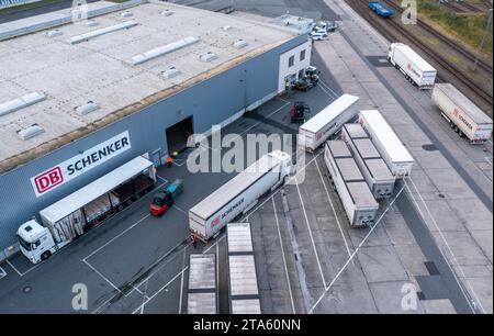 Rostock, Deutschland. November 2023. Lkw des Logistikunternehmens DB Schenker werden auf dem Gelände des Logistikzentrums im Seehafen entladen. (Luftaufnahme mit Drohne) die Logistikgesellschaft der Deutschen Bahn betreibt mehrere Logistikzentren in Mecklenburg-Vorpommern. Quelle: Jens Büttner/dpa/Alamy Live News Stockfoto
