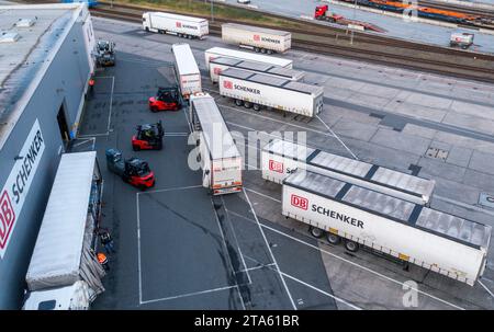Rostock, Deutschland. November 2023. Lkw des Logistikunternehmens DB Schenker werden auf dem Gelände des Logistikzentrums im Seehafen entladen. (Luftaufnahme mit Drohne) die Logistikgesellschaft der Deutschen Bahn betreibt mehrere Logistikzentren in Mecklenburg-Vorpommern. Quelle: Jens Büttner/dpa/Alamy Live News Stockfoto