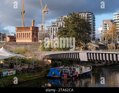 Stadterneuerung in London UK. Regent's Canal am Kings Cross, mit neu erbauten Wohnblocks und historischem viktorianischen Backsteinturm auf der linken Seite. Stockfoto