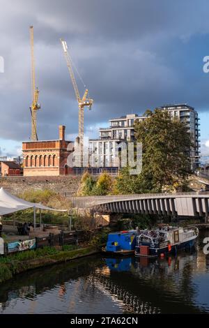 Stadterneuerung in London UK. Regent's Canal am Kings Cross, mit neu erbauten Wohnblocks und historischem viktorianischen Backsteinturm auf der linken Seite. Stockfoto