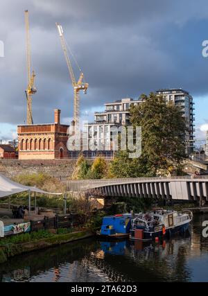 Stadterneuerung in London UK. Regent's Canal am Kings Cross, mit neu erbauten Wohnblocks und historischem viktorianischen Backsteinturm auf der linken Seite. Stockfoto