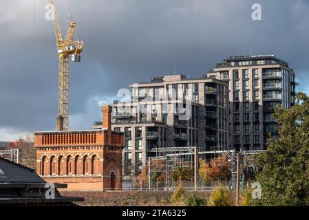 Stadterneuerung in London UK. Regent's Canal am Kings Cross, mit neu erbauten Wohnblocks und historischem viktorianischen Backsteinturm auf der linken Seite. Stockfoto