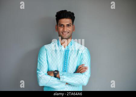 Porträt eines lächelnden Indianers in hellblauer Kurta, der Arme kreuzt und in die Kamera blickt Stockfoto