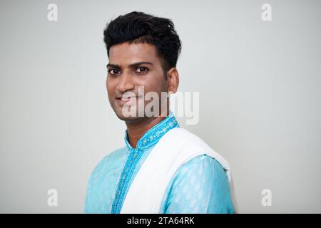 Fröhlicher indischer Mann in blauer Kurta posiert vor weißem Hintergrund Stockfoto