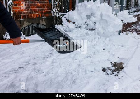 Rendsburg, Deutschland. November 2023. Ein Mann entfernt Schnee von einem Bürgersteig im Stadtzentrum mit einer Schaufel. Frank Molter/dpa/Alamy Live News Stockfoto