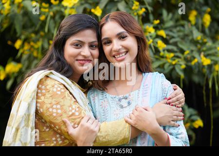 Porträt einer lächelnden Indianerin, die den besten Freund umarmt und in die Kamera schaut Stockfoto