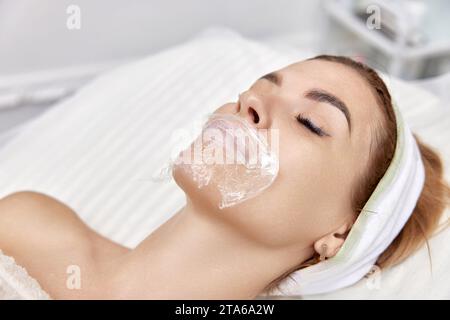 Frau mit Narkosecreme auf den Lippen vor Injektion von Hyaluronsäure. Lippenvergrößerungsverfahren Stockfoto